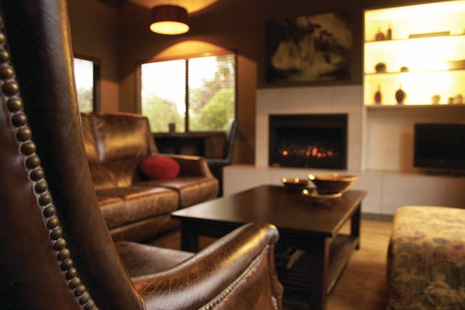 Peppers Parehua Wairarapa sitting room with brown leather chairs and fireplace