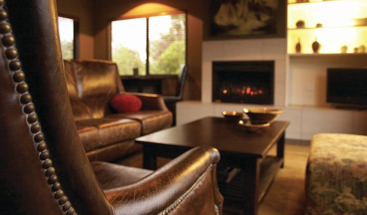 Peppers Parehua Wairarapa sitting room with brown leather chairs and fireplace