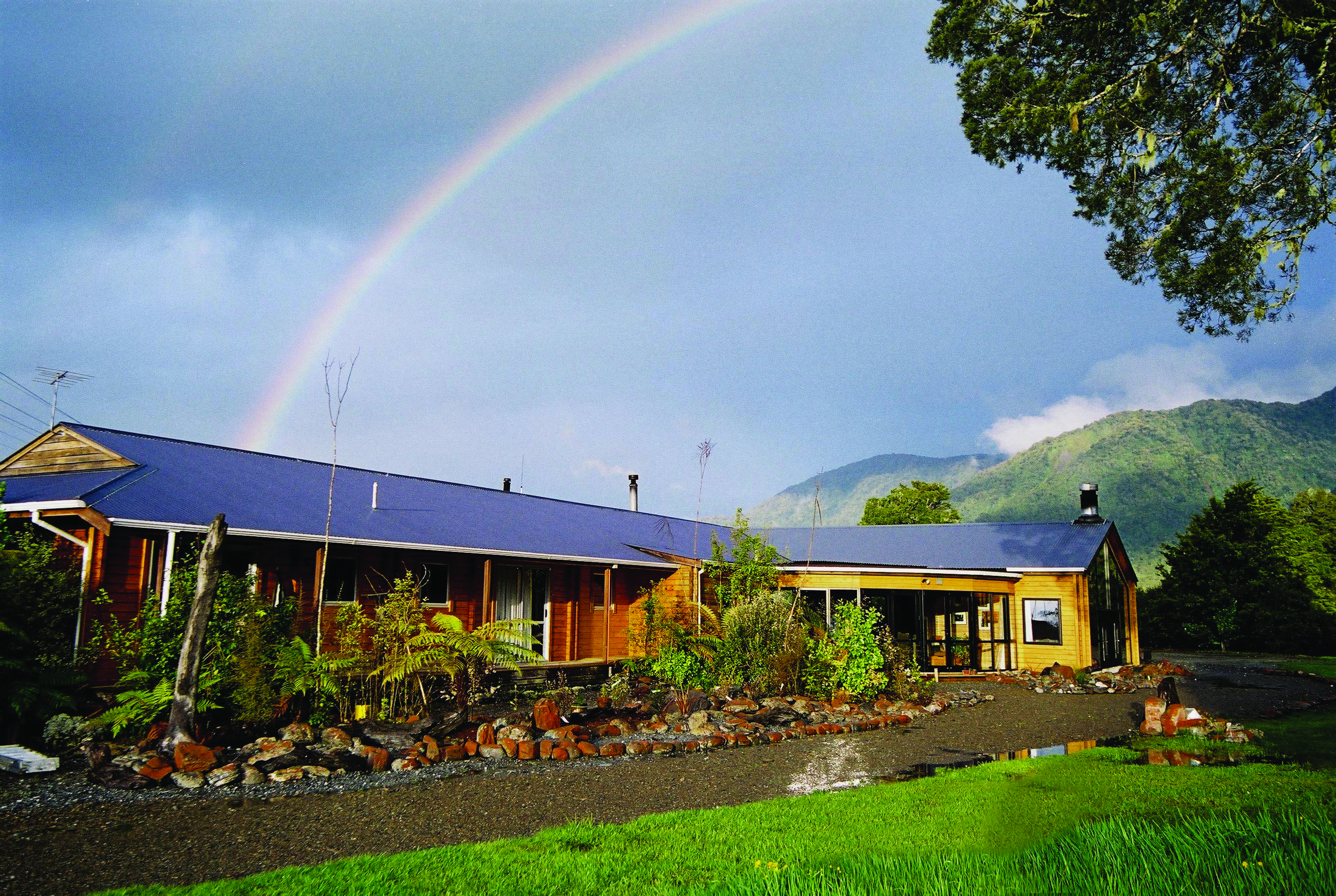 Exterior shot of Westwood Country House, lush lawn, lodge, rainbow in the sky