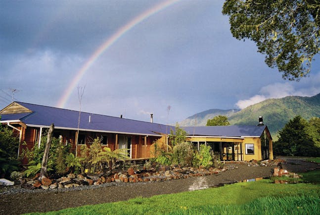 Exterior shot of Westwood Country House, lush lawn, lodge, rainbow in the sky
