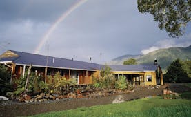 Exterior shot of Westwood Country House, lush lawn, lodge, rainbow in the sky