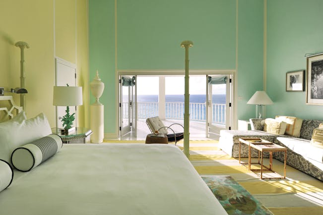 Malliouhana premium room with pastel colours, large double bed and sofa, with balcony with sea views