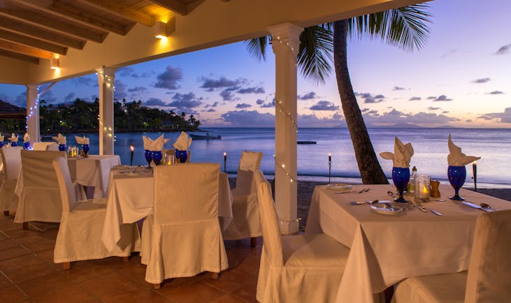 White dining tables at open air restaurant near palm tree