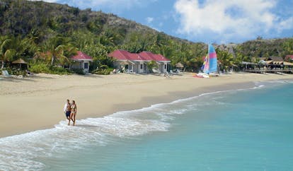 Galley Bay Antigua couple walking on beach san clear blue water boats