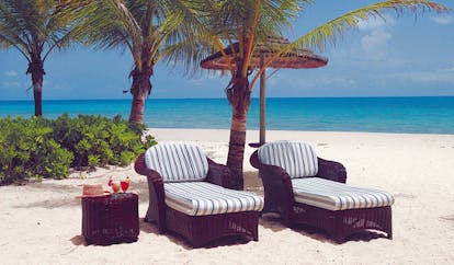 Galley Bay Antigua sun loungers on white sandy beach palm trees ocean in background