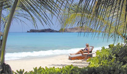 Galley Bay Antigua woman sun bathing on the beach reading a book