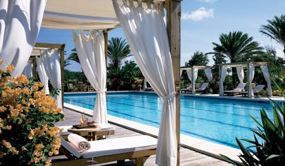 Jumby Bay Antigua poolside canopied sun loungers palm trees