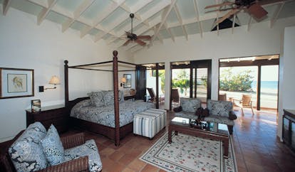Jumby Bay Antigua suite interior four poster bed armchairs terrace