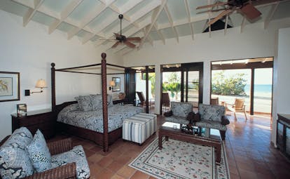 Jumby Bay Antigua suite interior four poster bed armchairs terrace