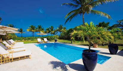Jumby Bay Antigua tir na nog pool private pool sun loungers umbrellas palm trees