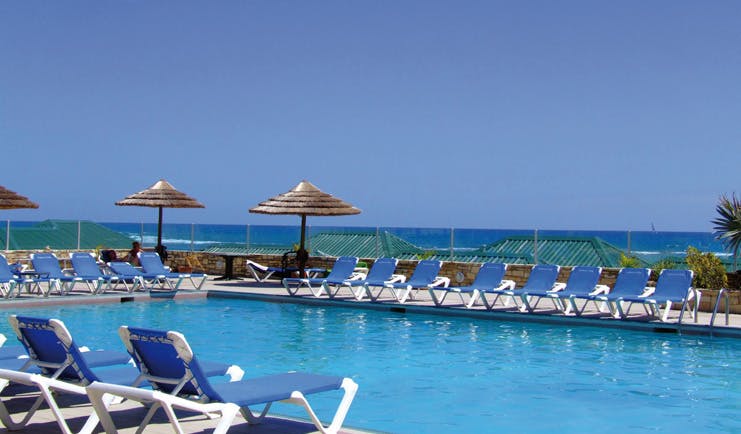 St James's Club Antigua poolside sun loungers umbrellas sea in background