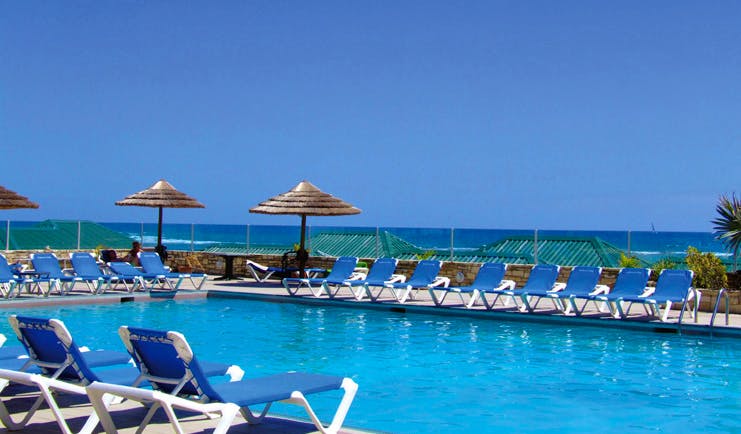 St James's Club Antigua poolside sun loungers umbrellas sea in background