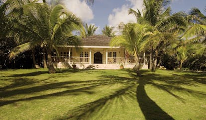 Kamalame Cay Bahamas lawn view of white bungalow and palm trees