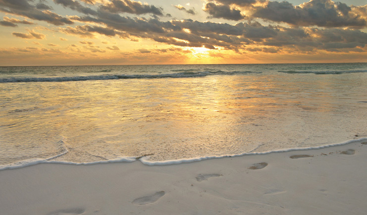 Pink Sands Bahamas sunrise over ocean footprints in the sand