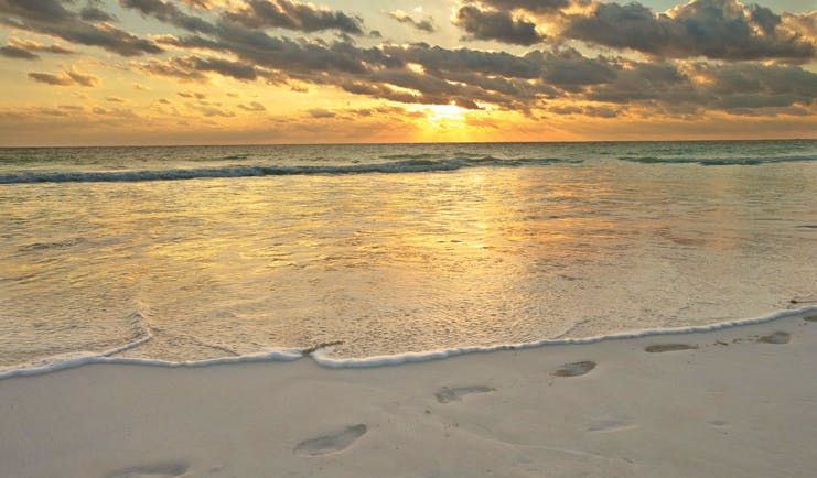 Pink Sands Bahamas sunrise over ocean footprints in the sand