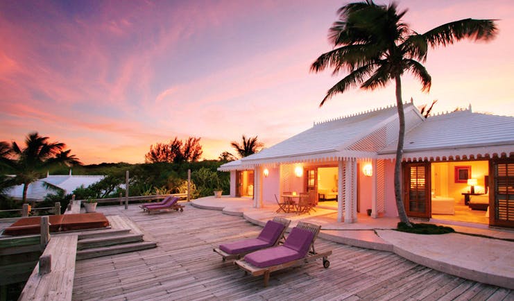 Pink Sands Bahamas villa exterior white bungalow decked area sun loungers palm trees