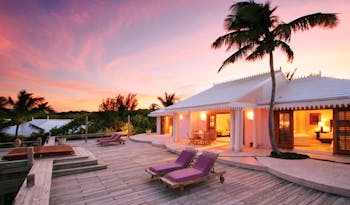 Pink Sands Bahamas villa exterior white bungalow decked area sun loungers palm trees