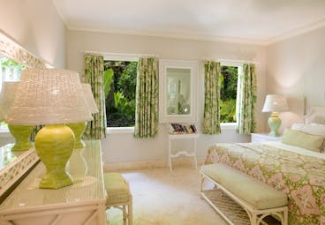 Garden view suite with double bed, lamp shades, green curtains and view of gardens out the windows