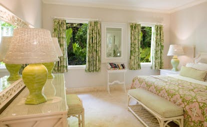Garden view suite with double bed, lamp shades, green curtains and view of gardens out the windows