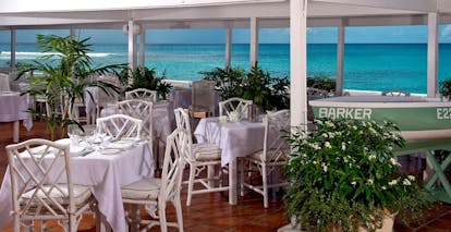Outdoor restaurant dining area with white tables and chairs set up for dining 