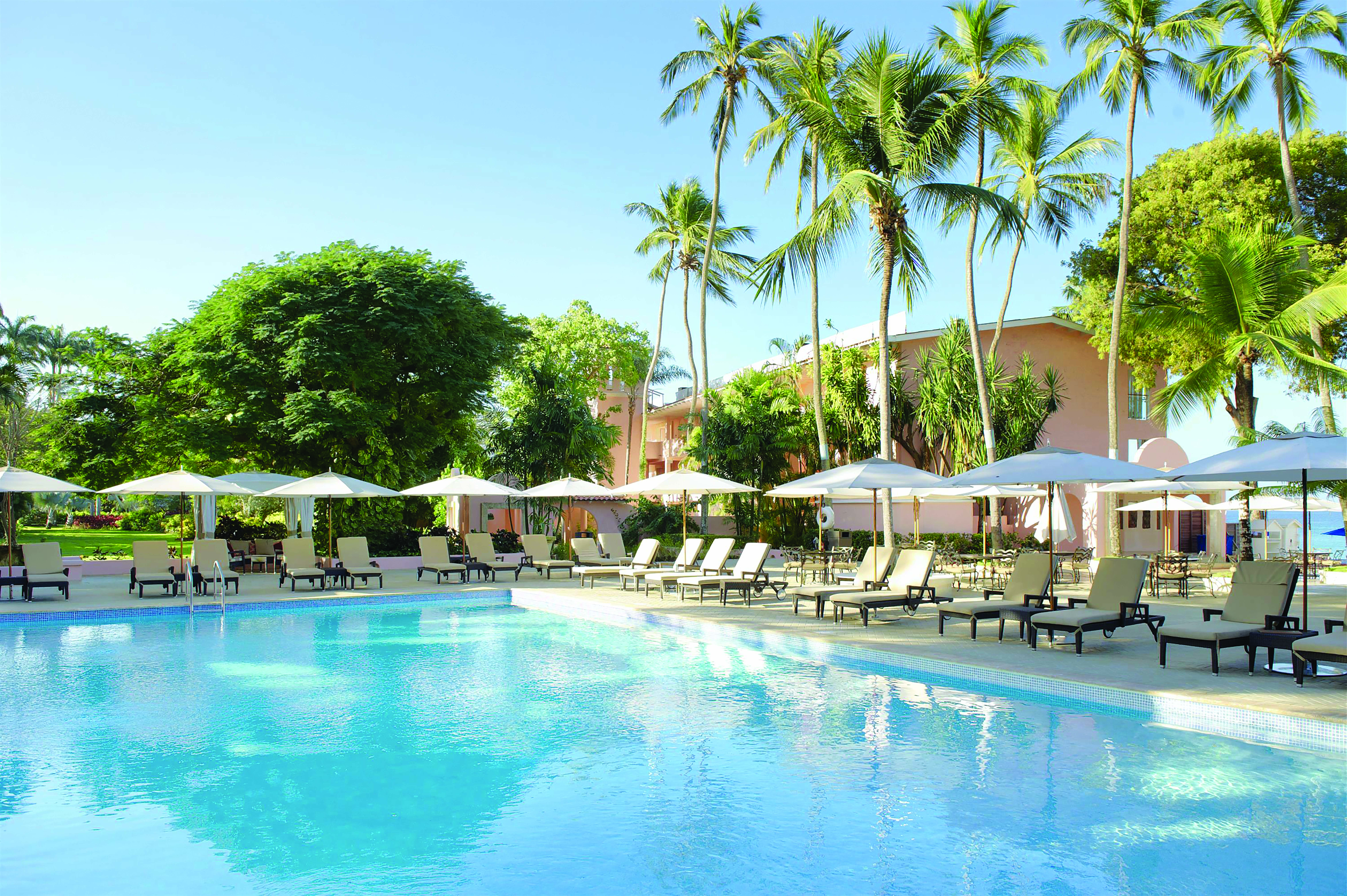 Fairmont Royal Pavilion Barbados pool sun loungers umbrellas and palm trees