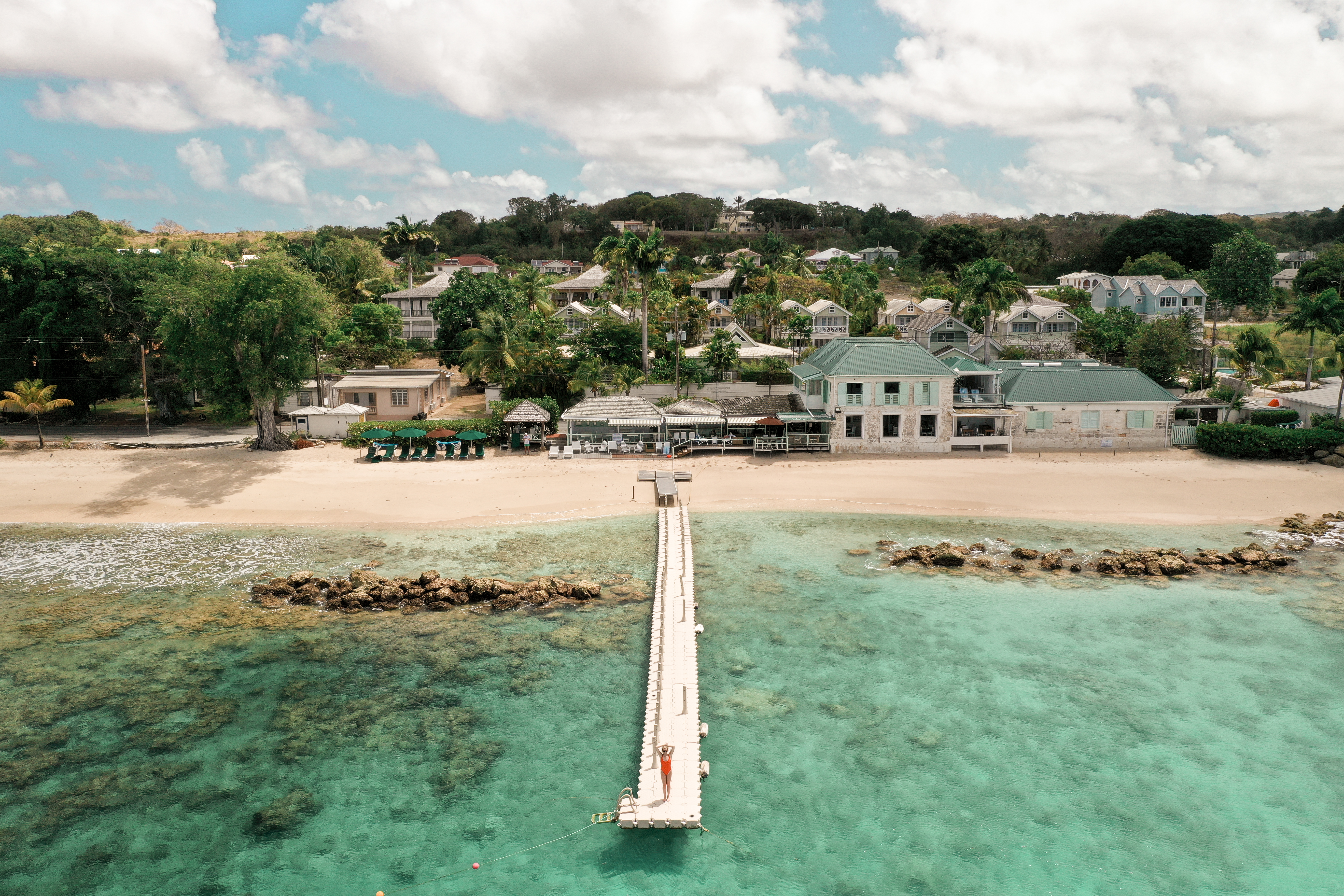 Little Good Harbour jetty extending into the clear blue sea, with the hotel buildings visible beyond the sand