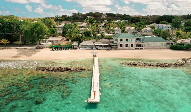 Little Good Harbour jetty extending into the clear blue sea, with the hotel buildings visible beyond the sand