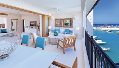 Patio in a  suite level room with tables and chairs laid out looking over clear blue water