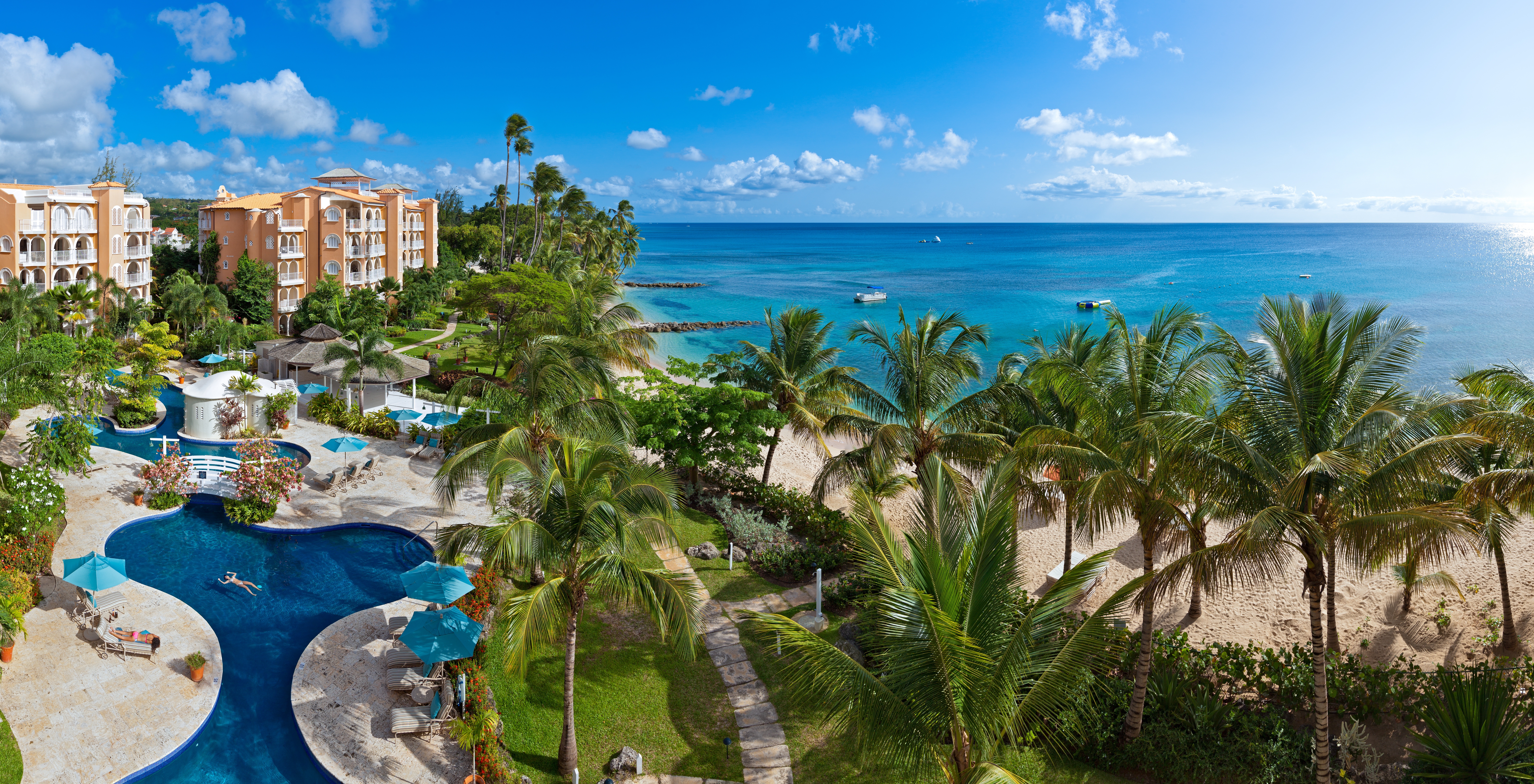 Aerial shot of St Peters Bay resort, pools, palm trees, hotel buildings, sea in background