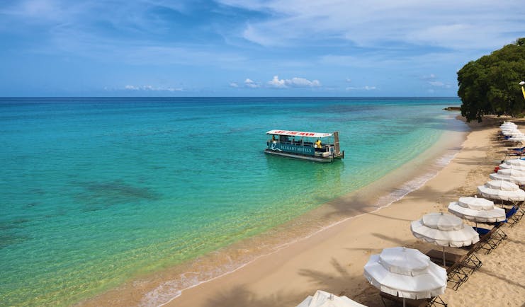 Treasure Beach Barbados beach and umbrellas boat on the water