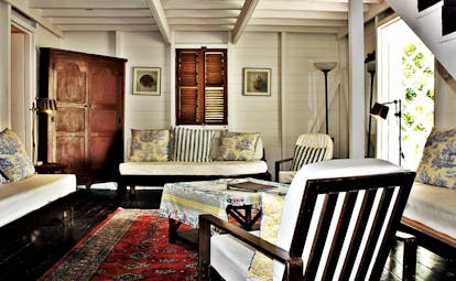 White wooden beamed ceiling and walls of lounge with traditional furniture at Hermitage Inn Nevis