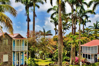 Cottages with red roofs and white balconies surrounded by palm trees at Hermitage Inn Nevis