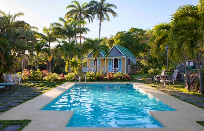 Swimming pool with Caribbean style houses and palm trees at Hermitage Inn Nevis