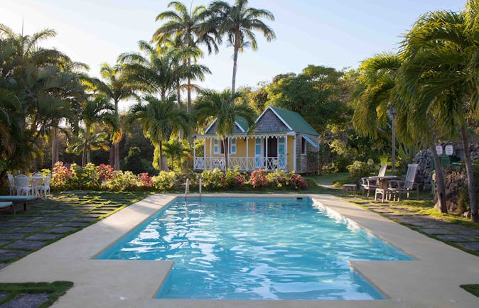 Swimming pool with Caribbean style houses and palm trees at Hermitage Inn Nevis