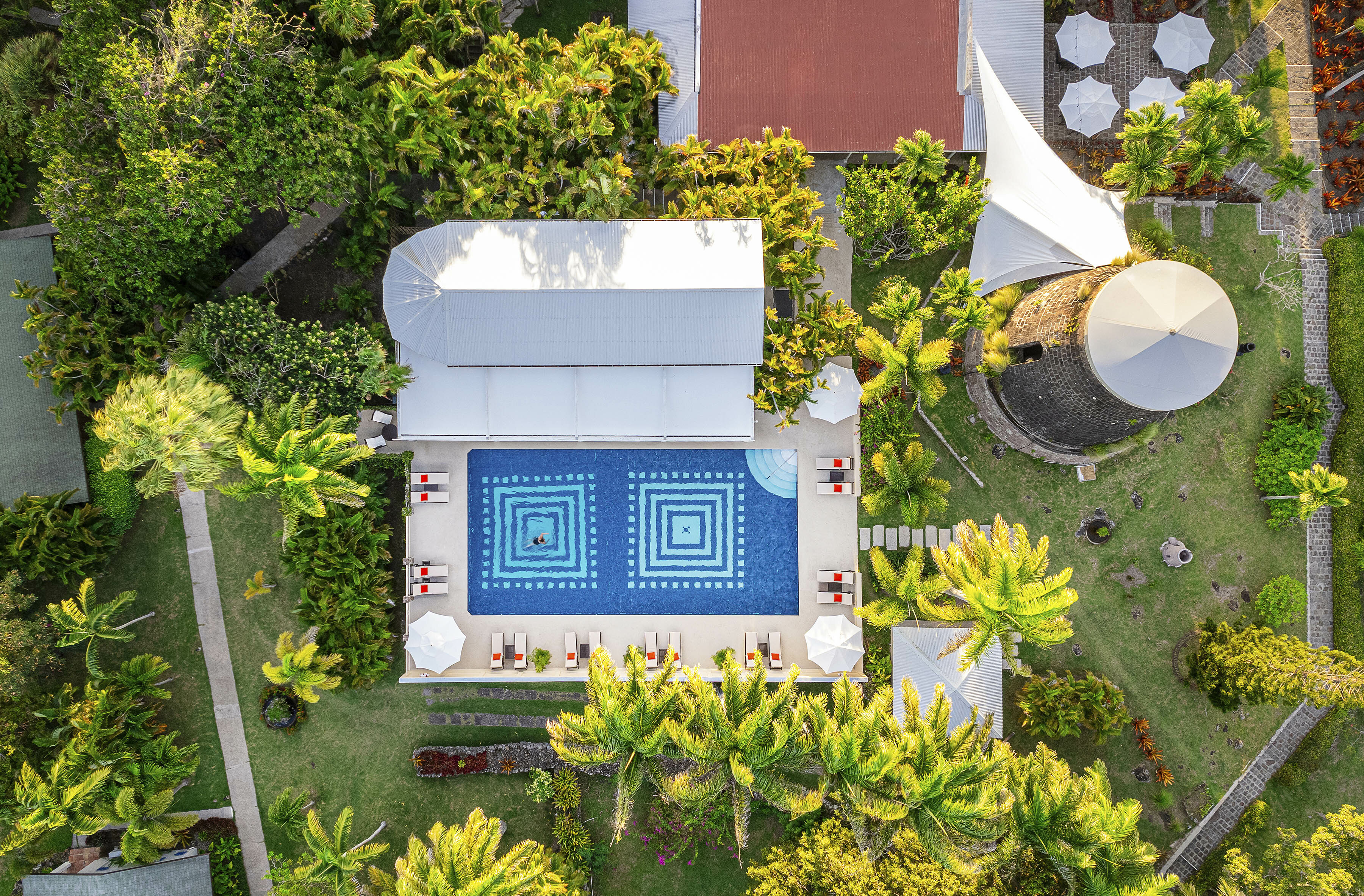 Montpelier Nevis aerial view of main hotel building, showing tiled poolside, blue water, sun loungers, and villa building