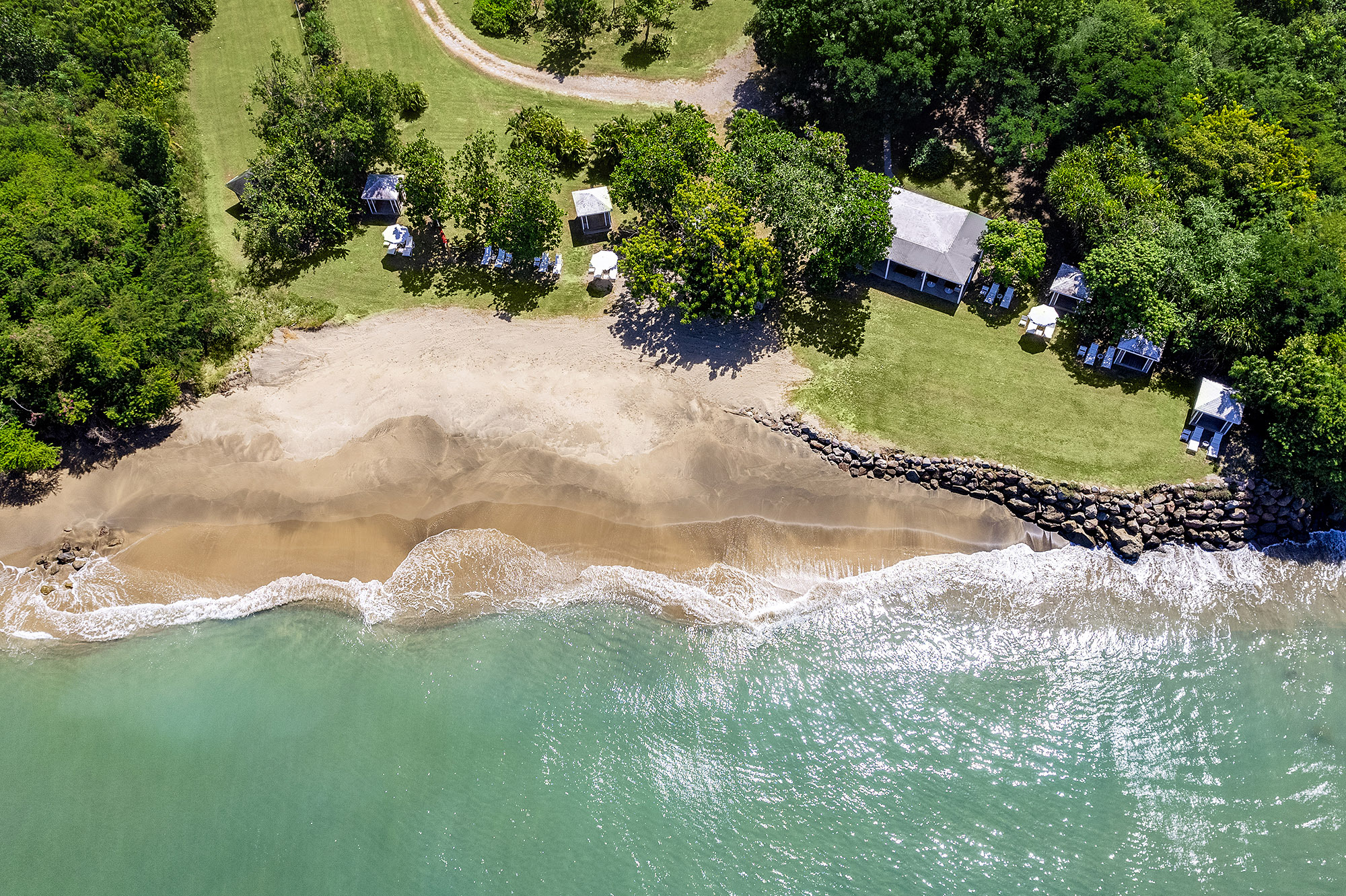 Montpelier Nevis aerial view of the beach with clear turquoise waters, sandy shore, and grassy hotel grounds