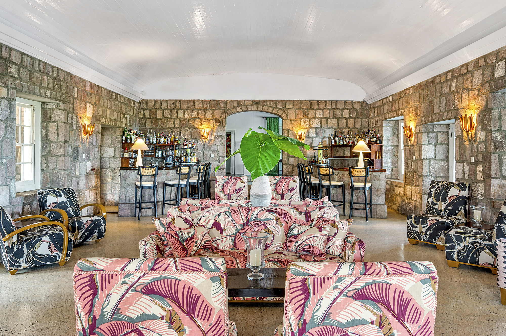 Montpelier Nevis Great Room with patterned pink, blue and cream seating, tiled walls, and atmospheric, warm lighting