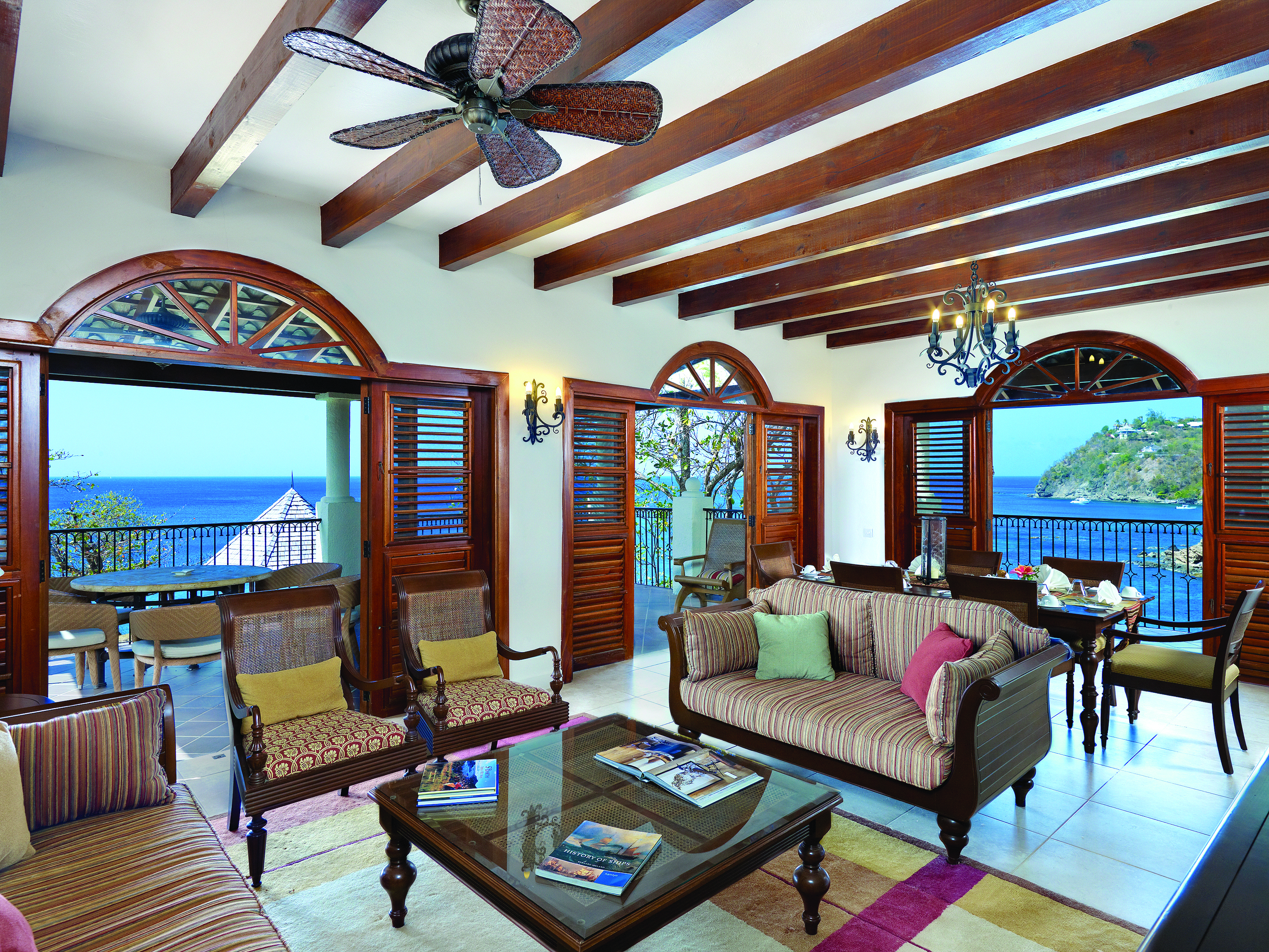 Cap Maison St Lucia suite lounge indoor seating area with sofa and armchairs leading 6o balcony with ocean views