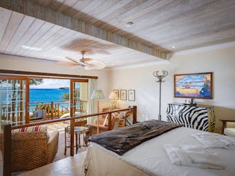 Bequia Beach Hotel guestroom, bed, lounge area, bright decor, balcony overlooking beach