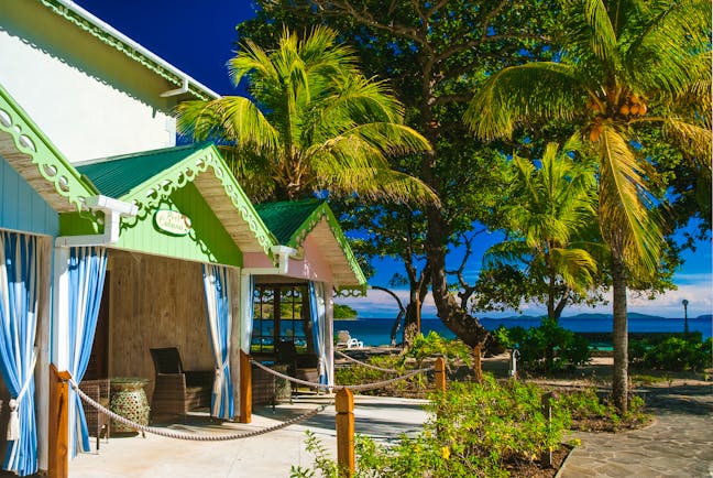 Bequia Beach Hotel pool cabanas, covered shaded outbuildings, brightly painted, palm trees