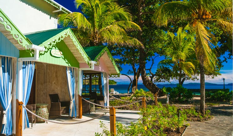 Bequia Beach Hotel pool cabanas, covered shaded outbuildings, brightly painted, palm trees