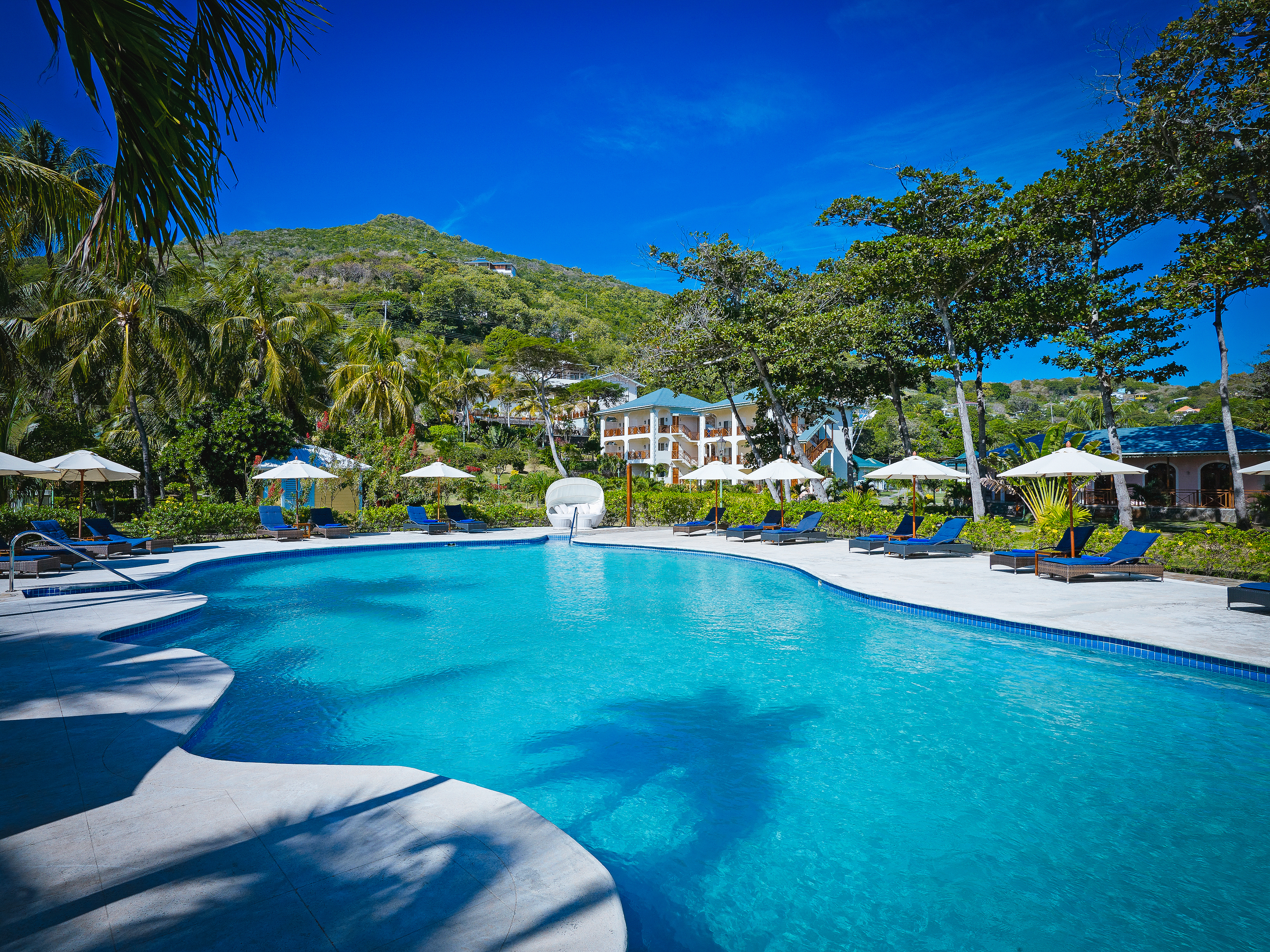 Bequia Beach Hotel pool, sun loungers, umbrellas, greenery