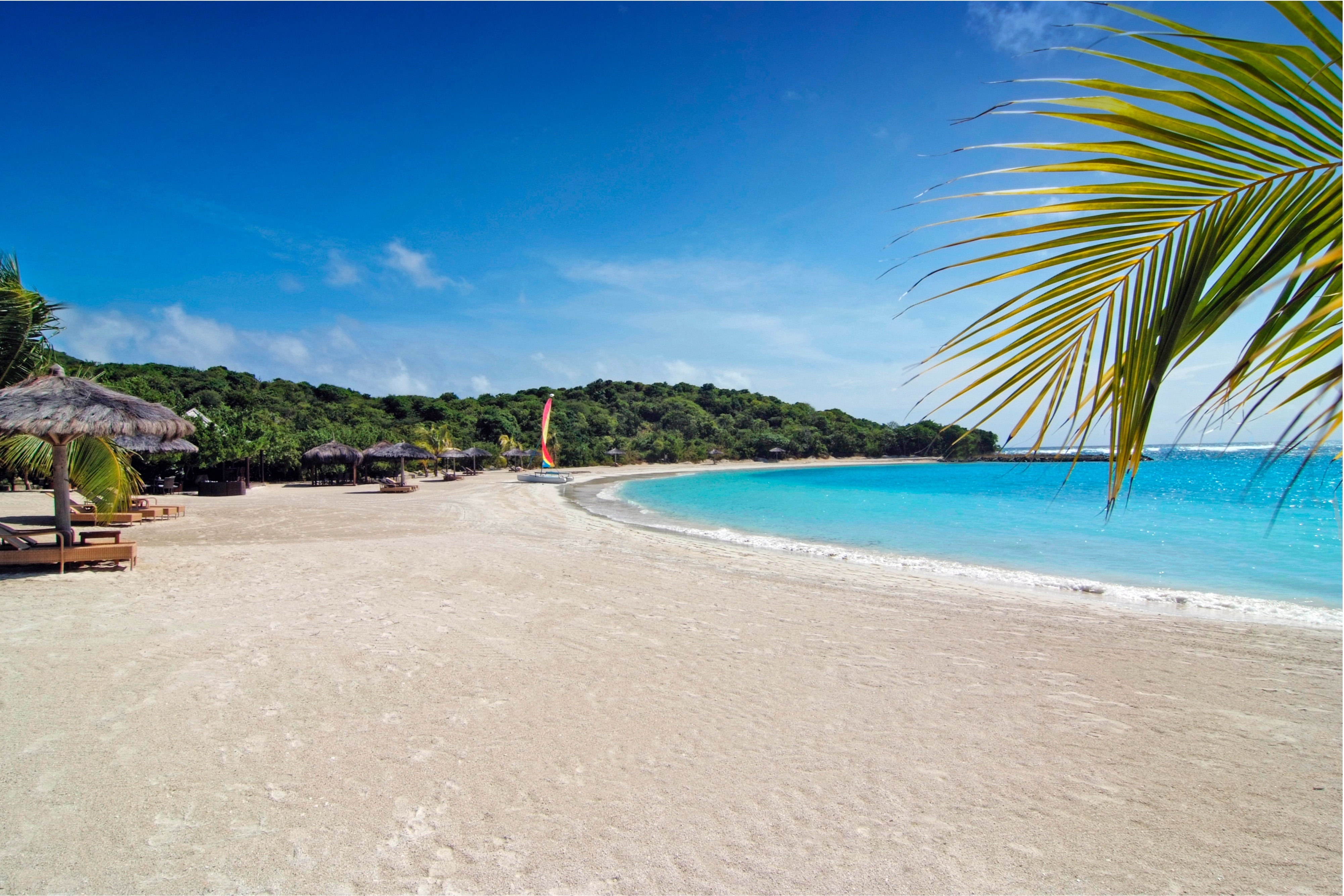 Canouan Estate beach with light golden sand and shallow waters