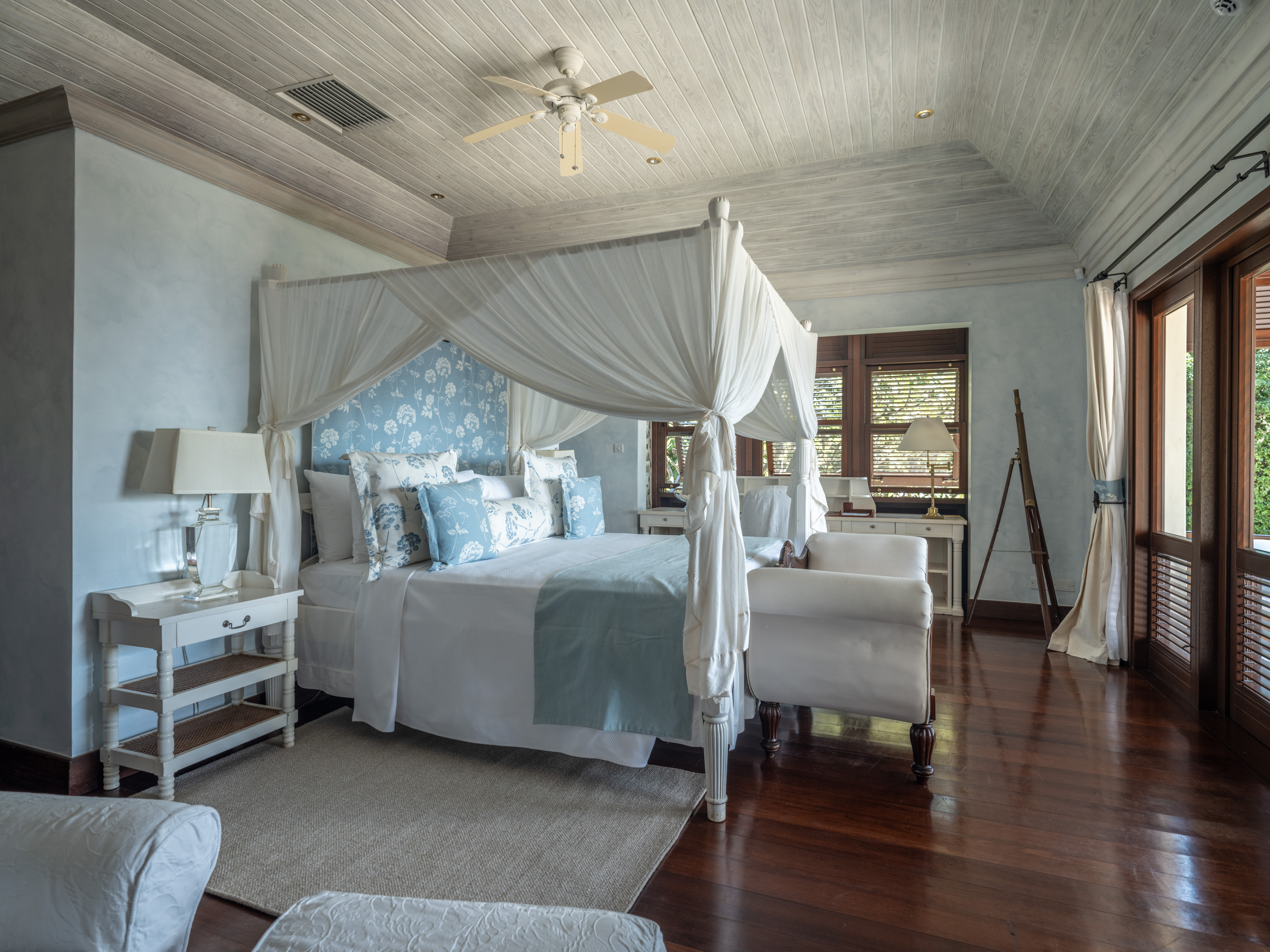 Canouan Estate bedroom with white and light blue colour scheme, wooden floors, and vaulted ceiling