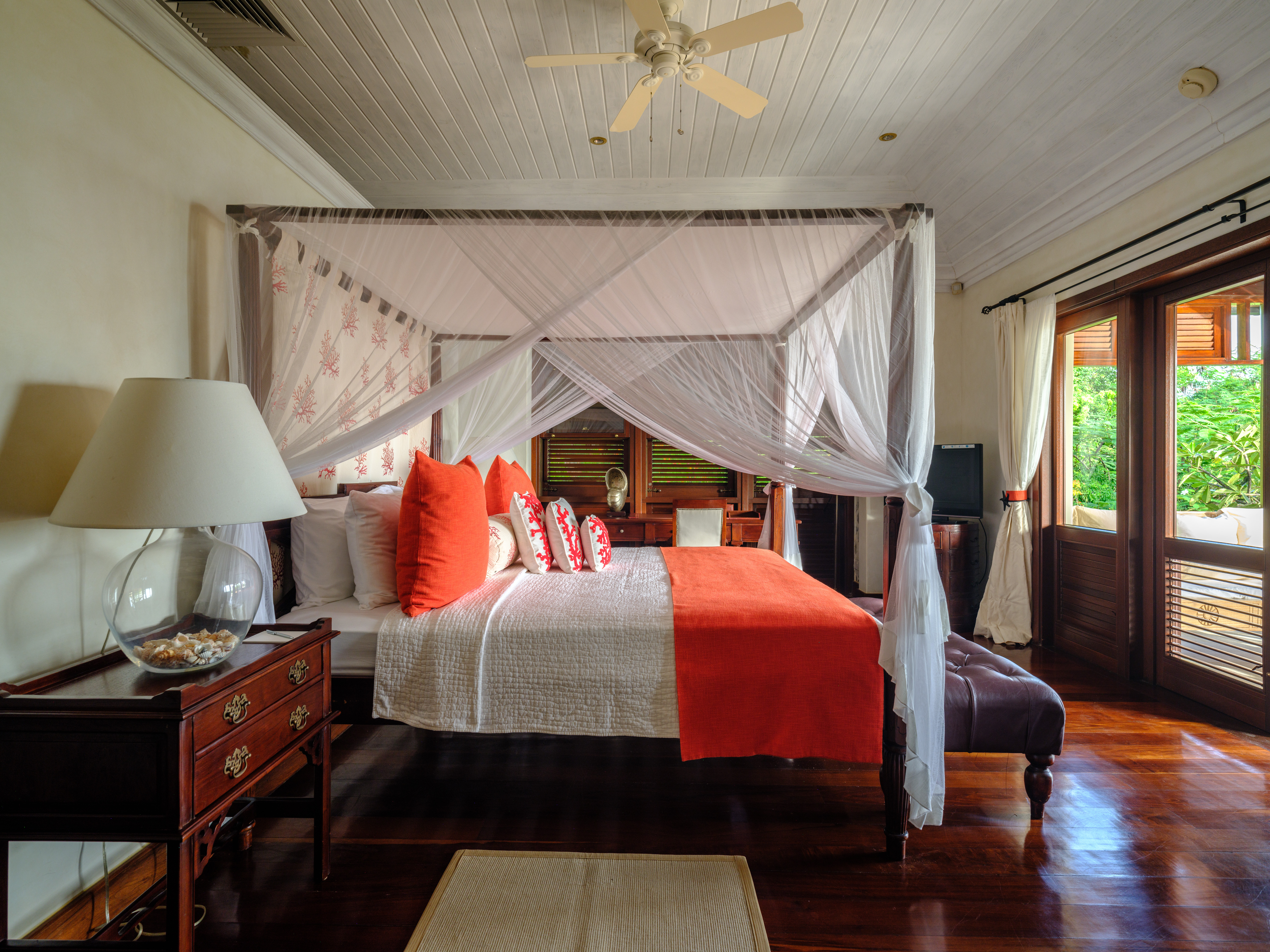Canouan Estate bedroom with wooden floor, neutral colour palette and pops and bright orange