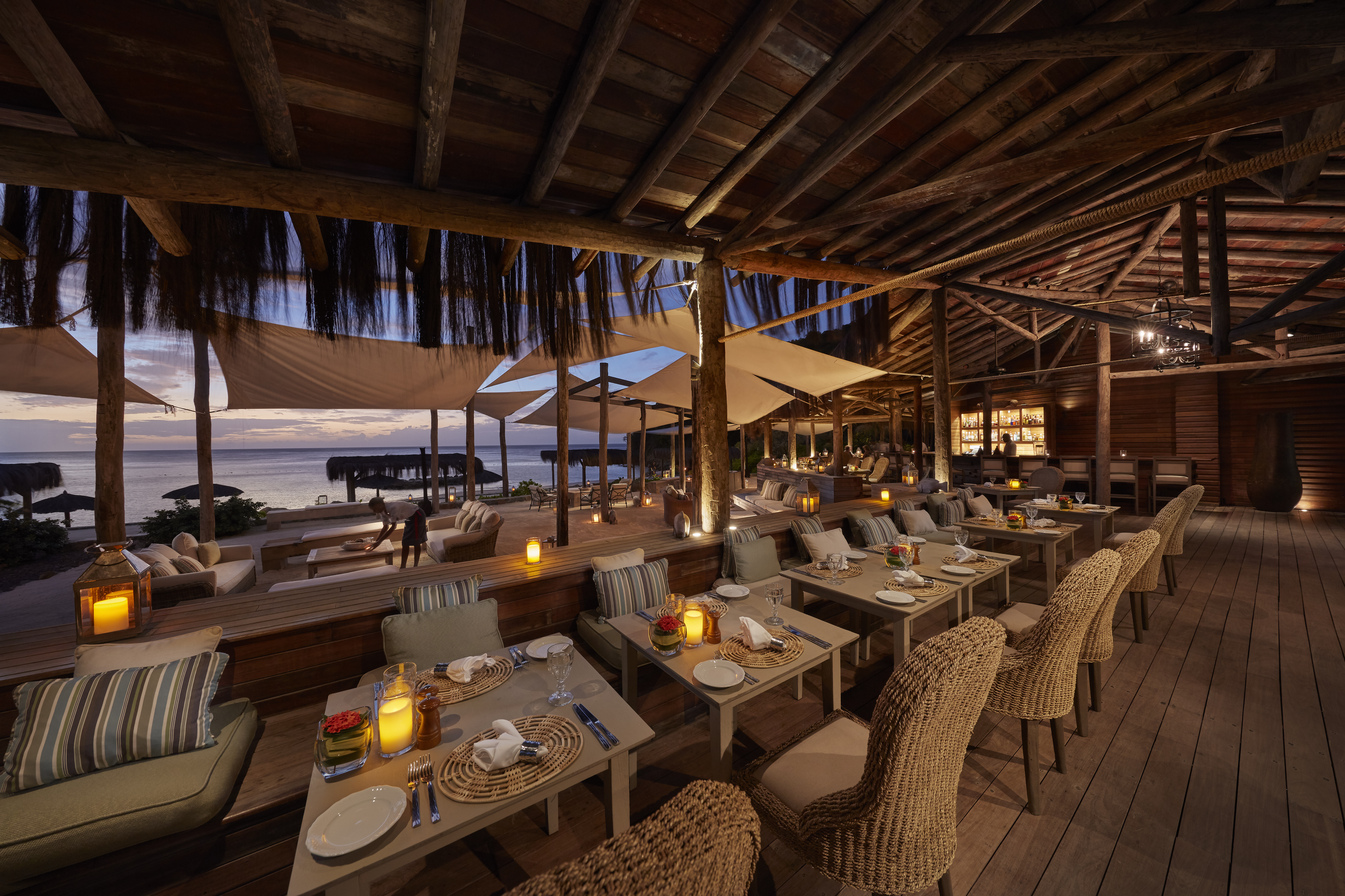 Canouan Estate restaurant in the evening under wooden canopy with candlelit tables