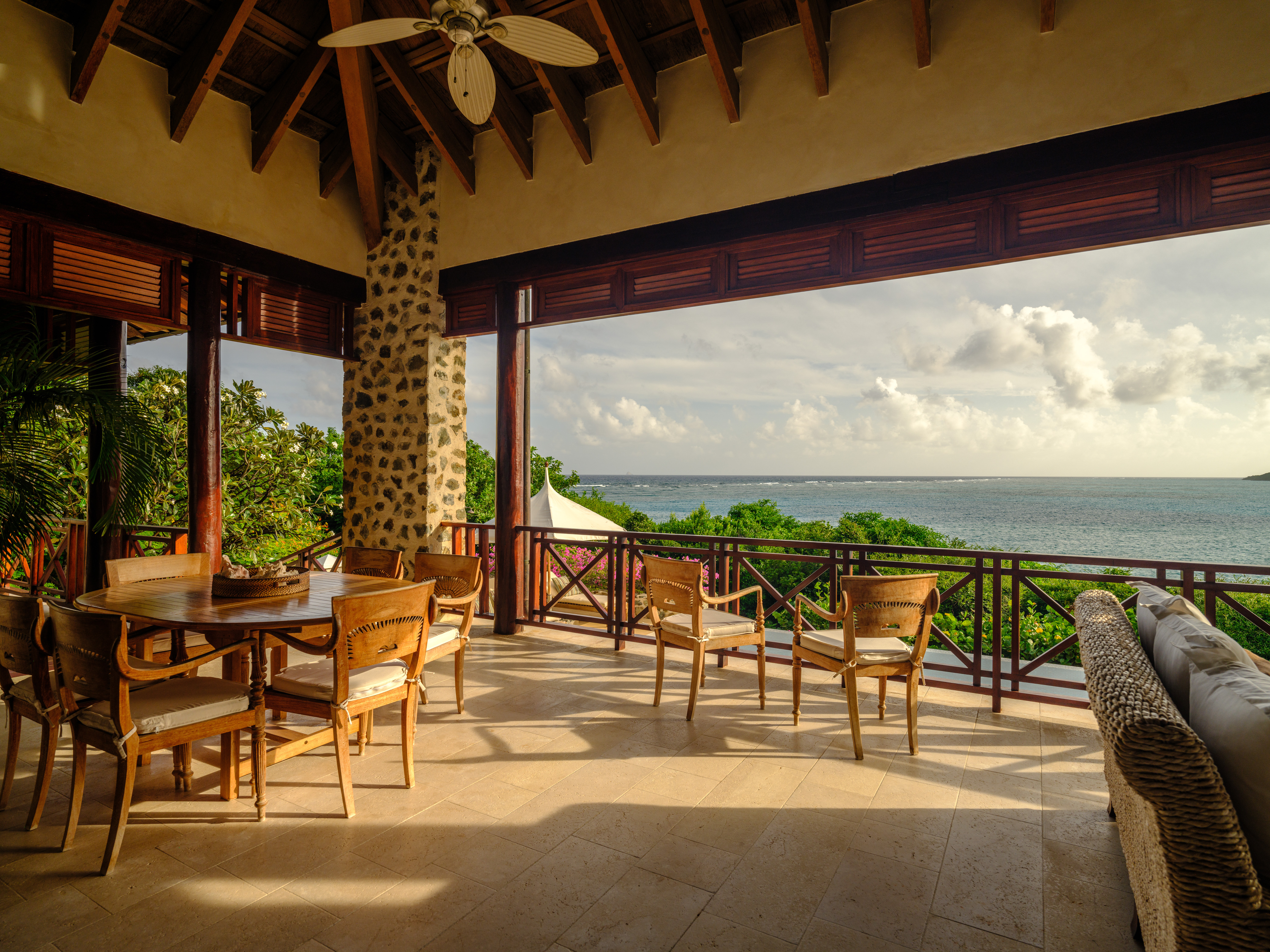 Canouan Estate terrace with stone pillars, vaulted wooden canopy, and tables and chairs