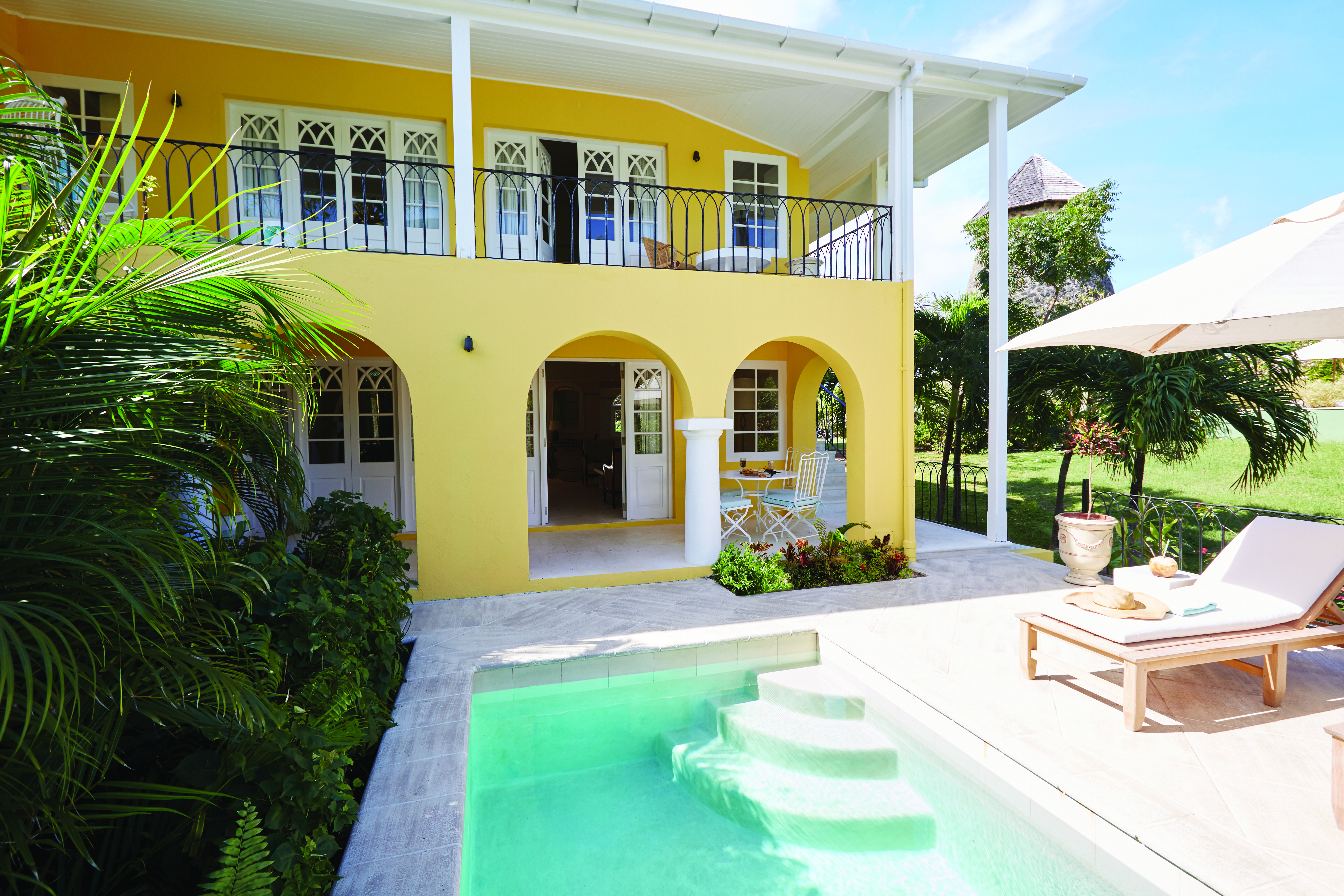 Cotton House St Vincent and the Grenadines villa yellow building pool sun lounger umbrella