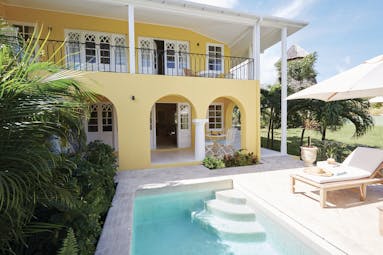 Cotton House St Vincent and the Grenadines villa yellow building pool sun lounger umbrella