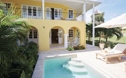 Cotton House St Vincent and the Grenadines villa yellow building pool sun lounger umbrella